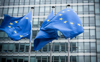 Drie Europese vlaggen wapperen voor het gebouw van de Europese Unie in Brussel